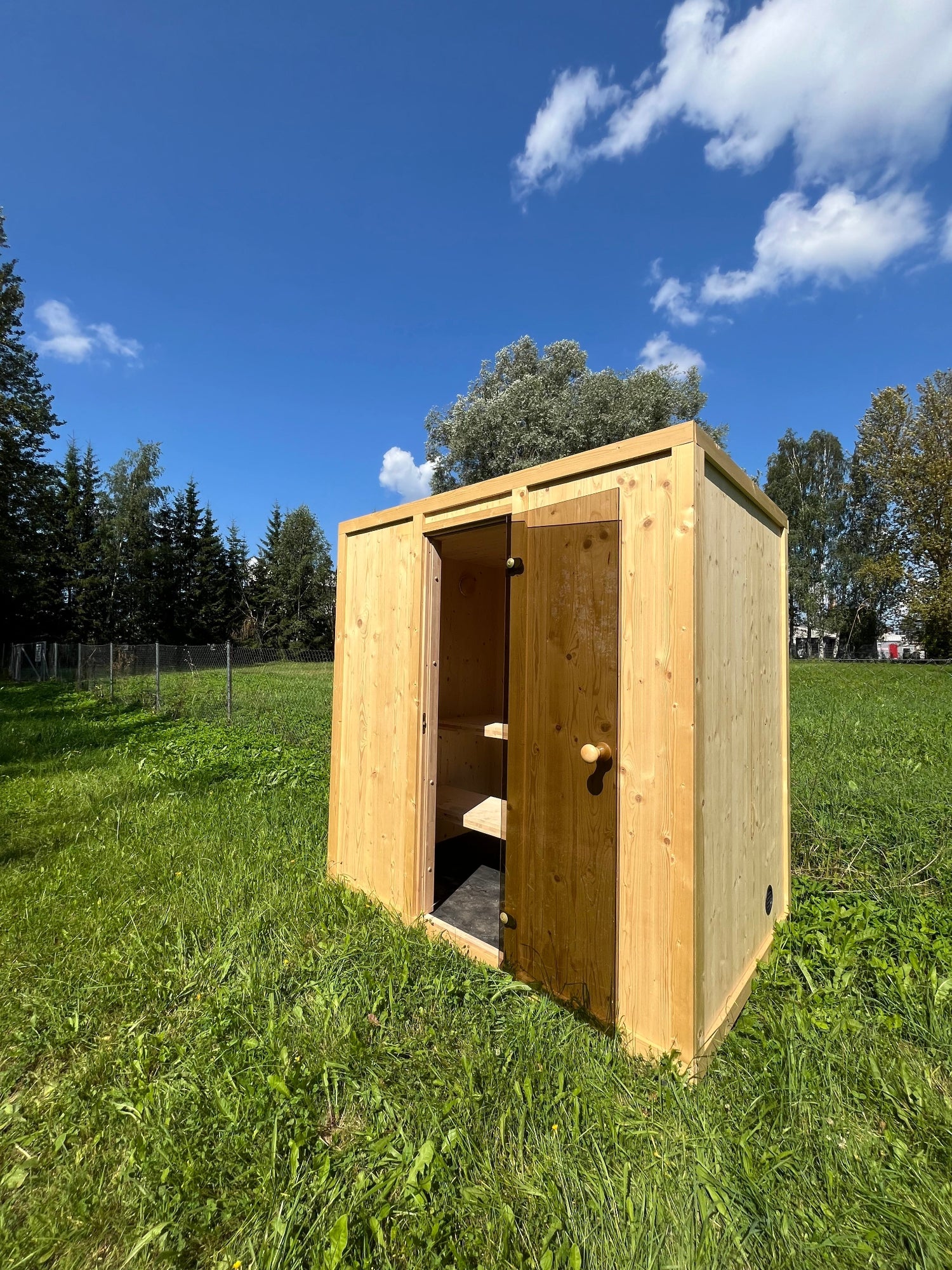 Vaalea CLT-rakenteinen pihasauna aurinkoisella nurmikolla- edullinen ja kompakti pihasaunaraktaisu