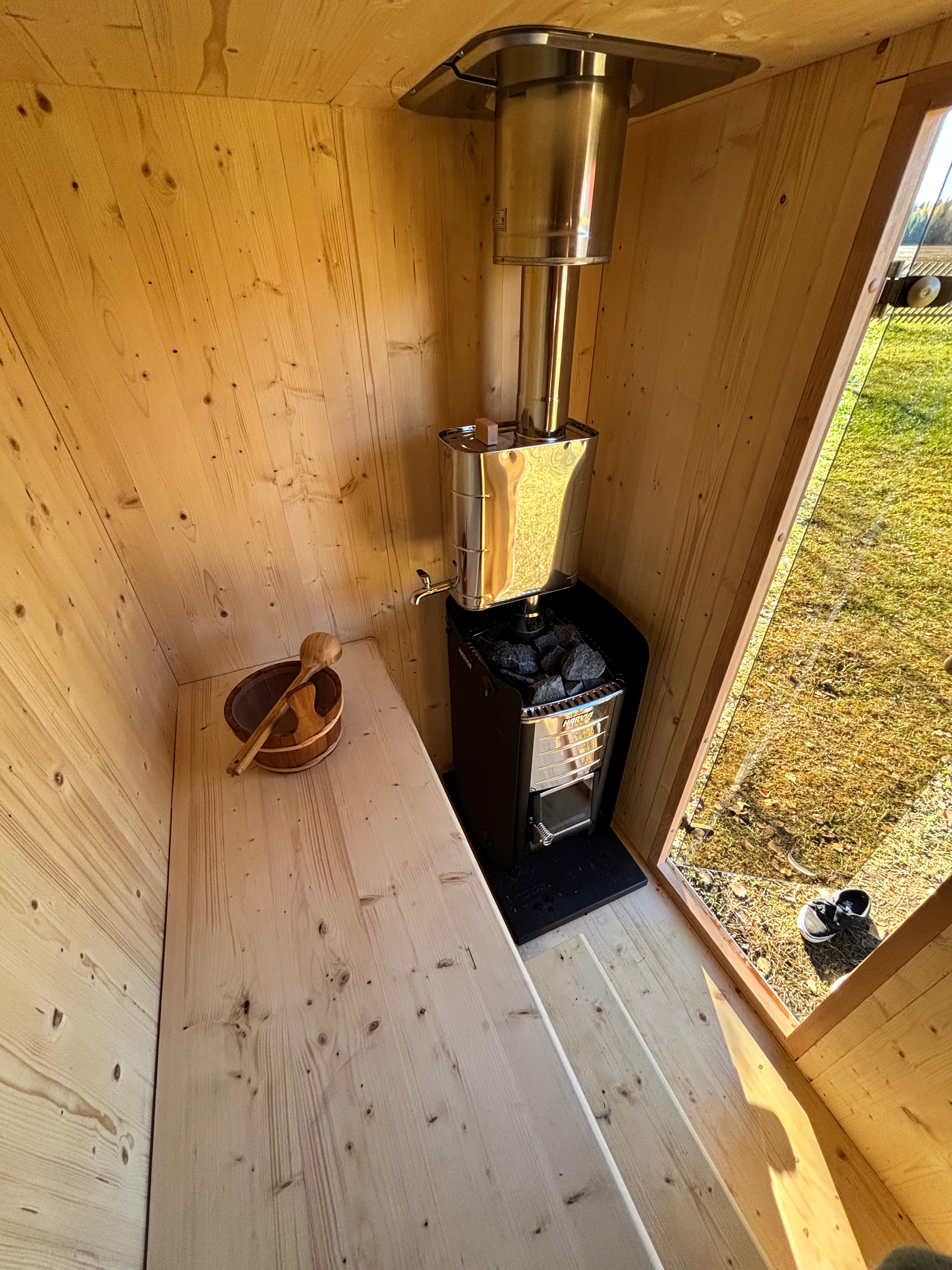 Vaalea CLT-saunan sisätila puukiukaalla - moderni ja luonnollinen design korostaa puhdasta puupintaa ja laadukasta viimeistelyä