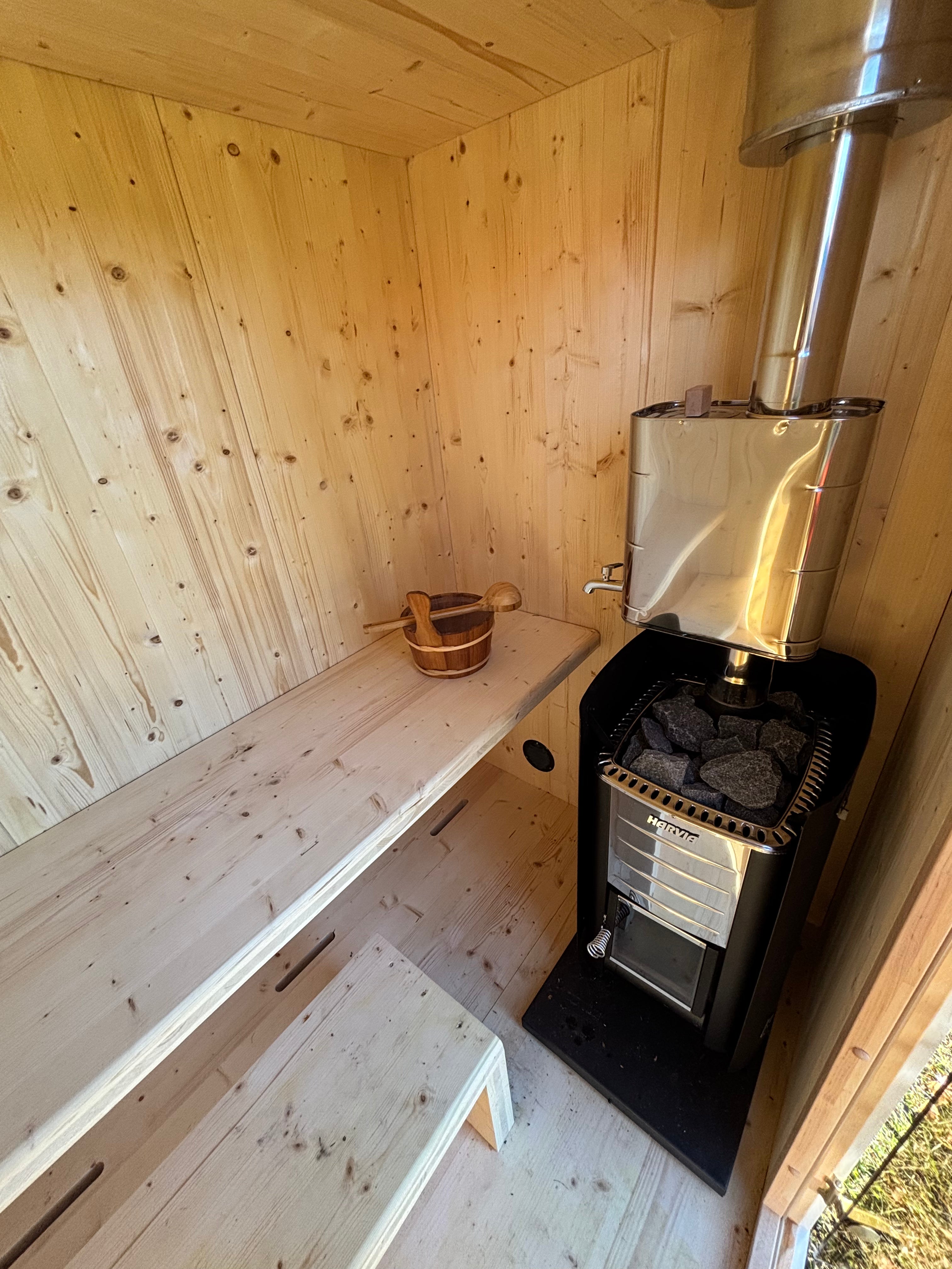 Edullinen puulämmitteinen ulkosauna sisältä – Harvia-kiuas varusteena